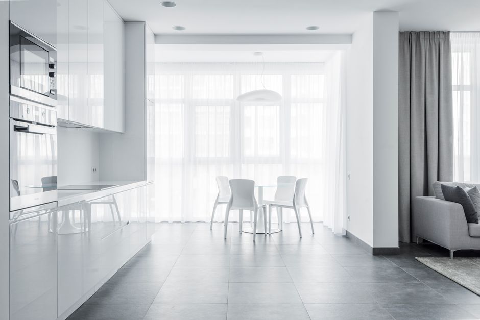 Bright minimalist dining area with white furniture and modern kitchen design.